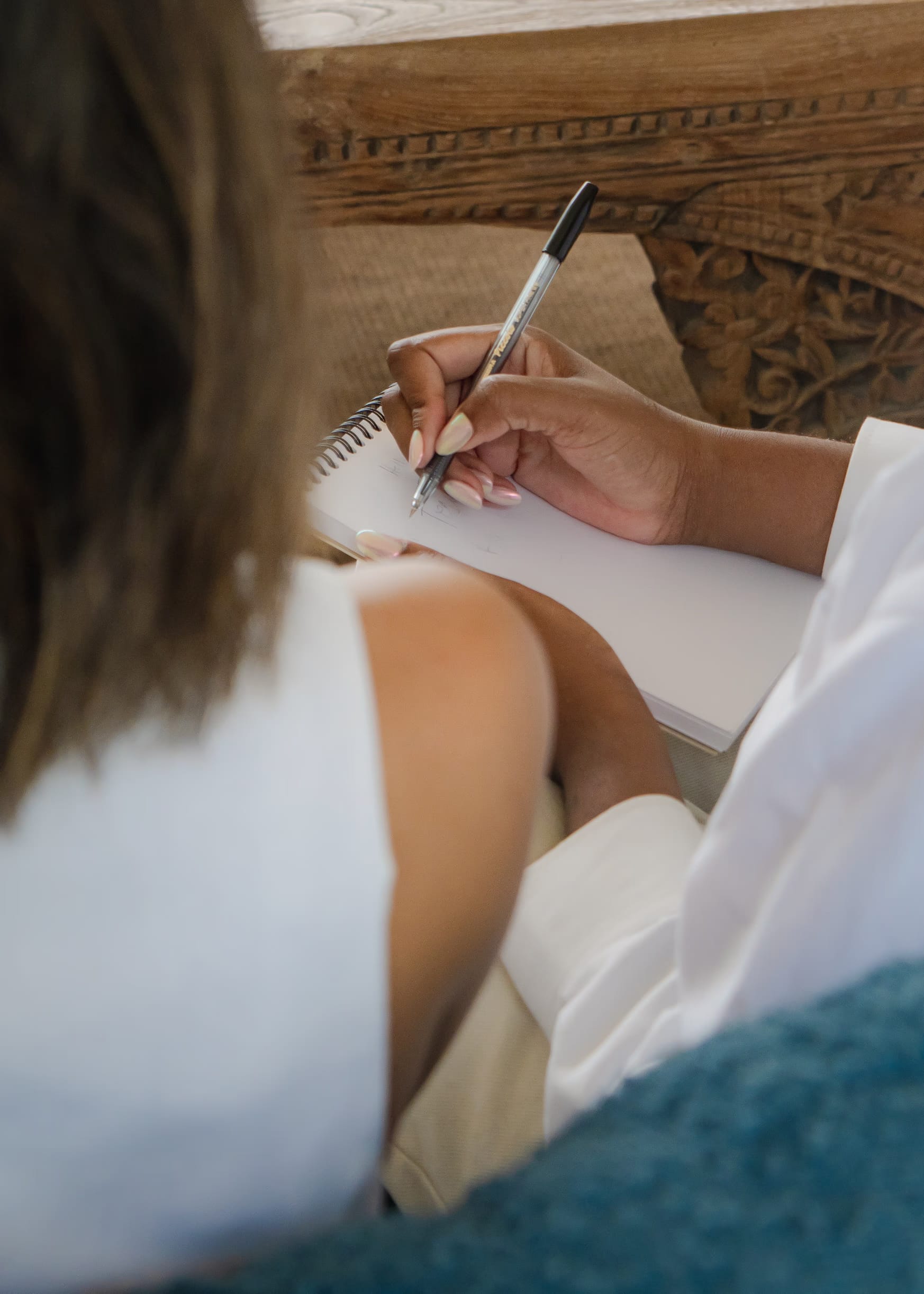 Two women in conversation, one taking notes in a notebook