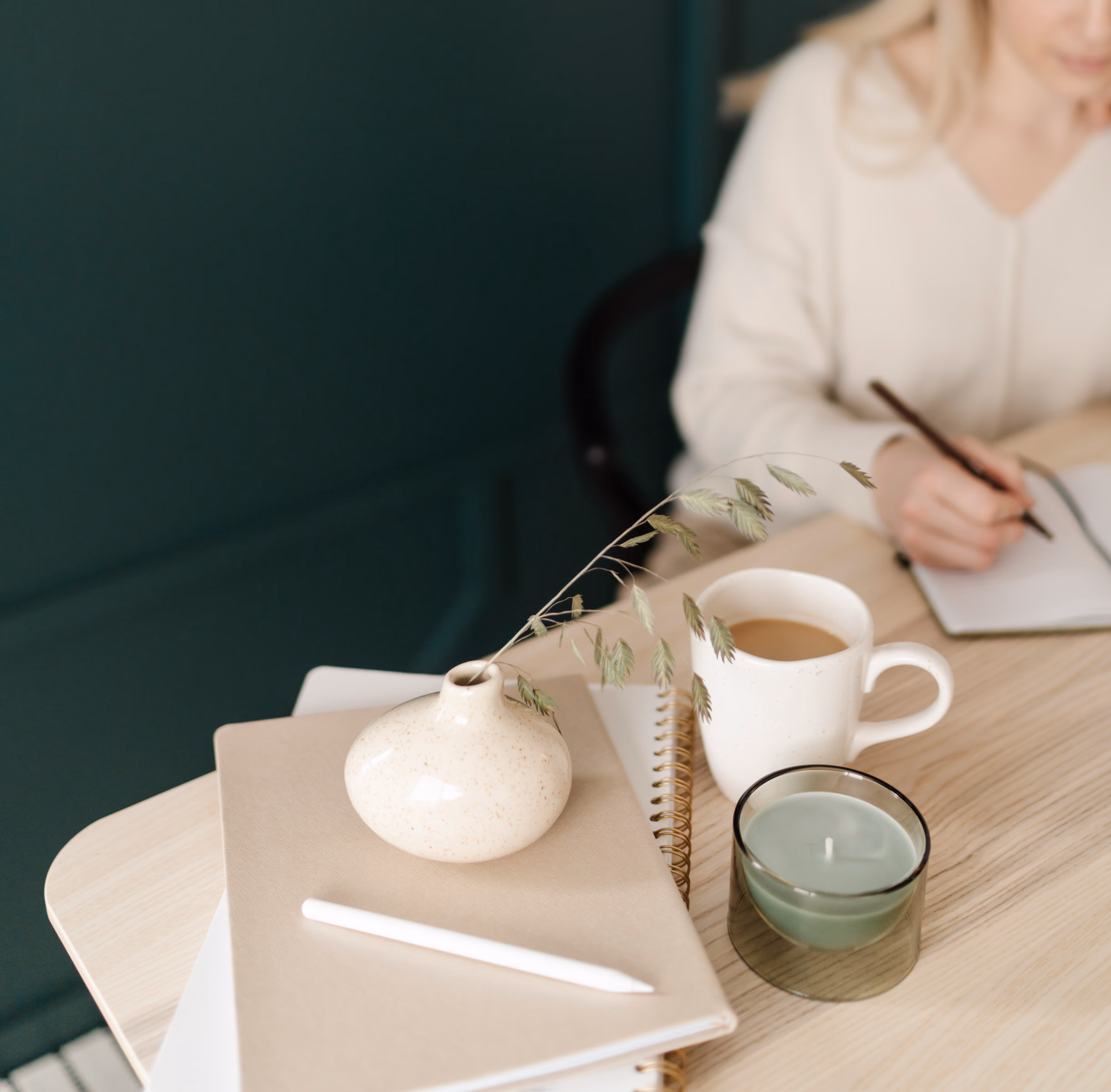 Woman in a white blouse taking notes while seated in a blue chair