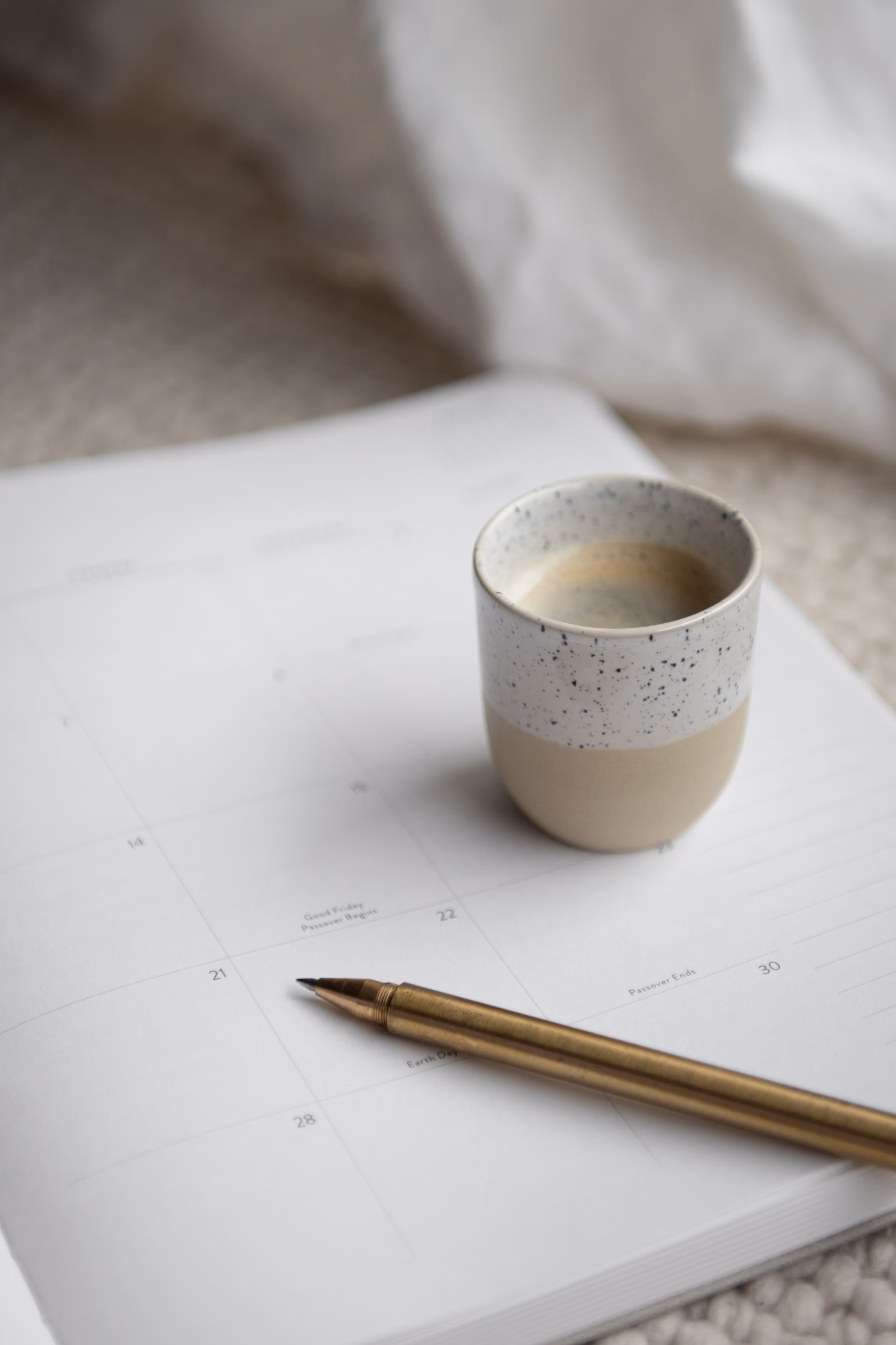 Speckled ceramic cup on a calendar with a gold pen